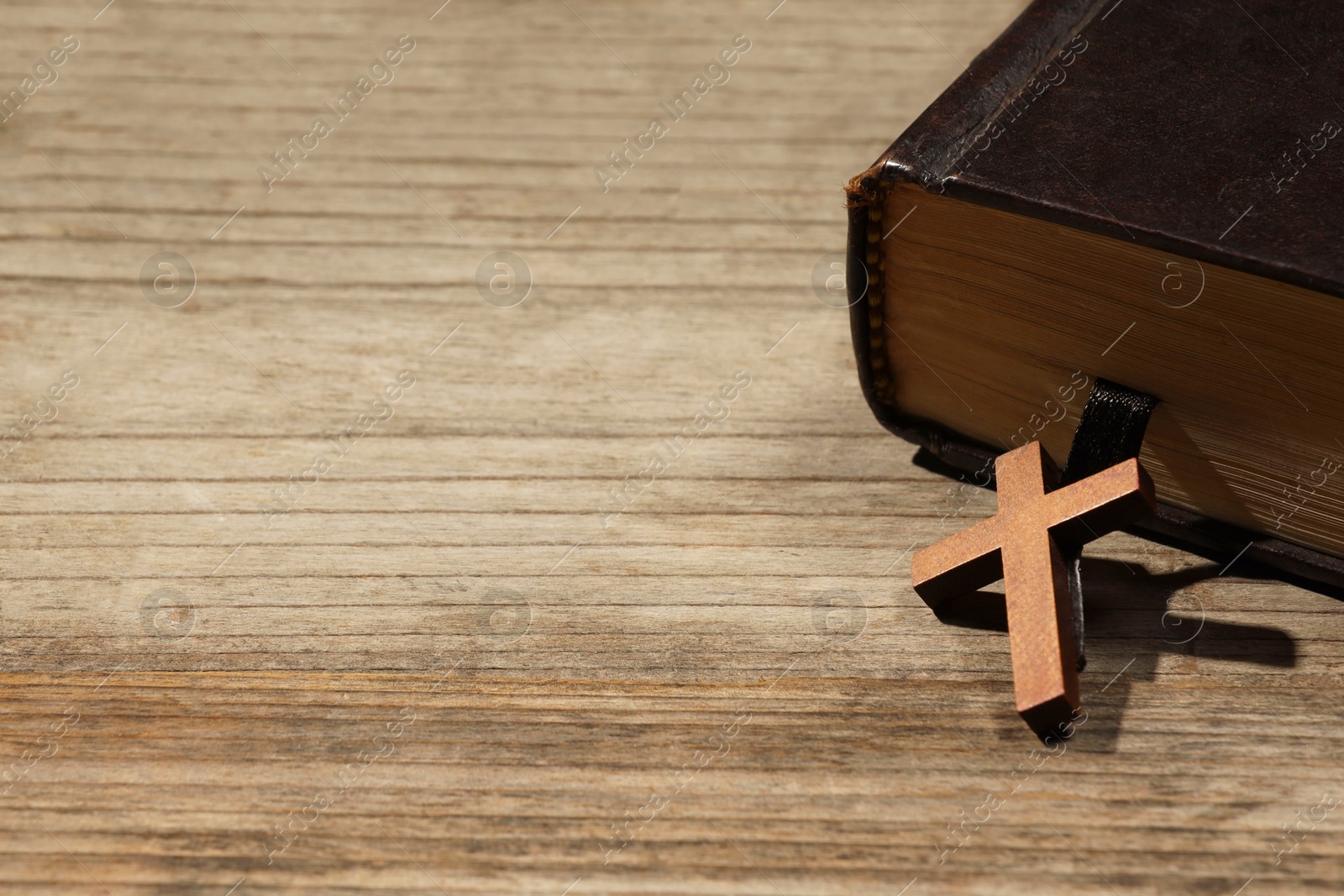 Photo of Bible and cross on wooden table, closeup with space for text. Religion of Christianity