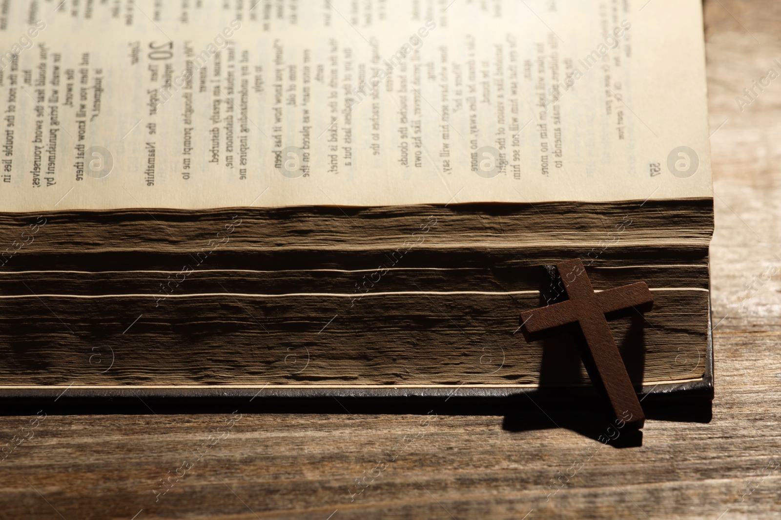 Photo of Bible and cross on wooden table, closeup. Religion of Christianity