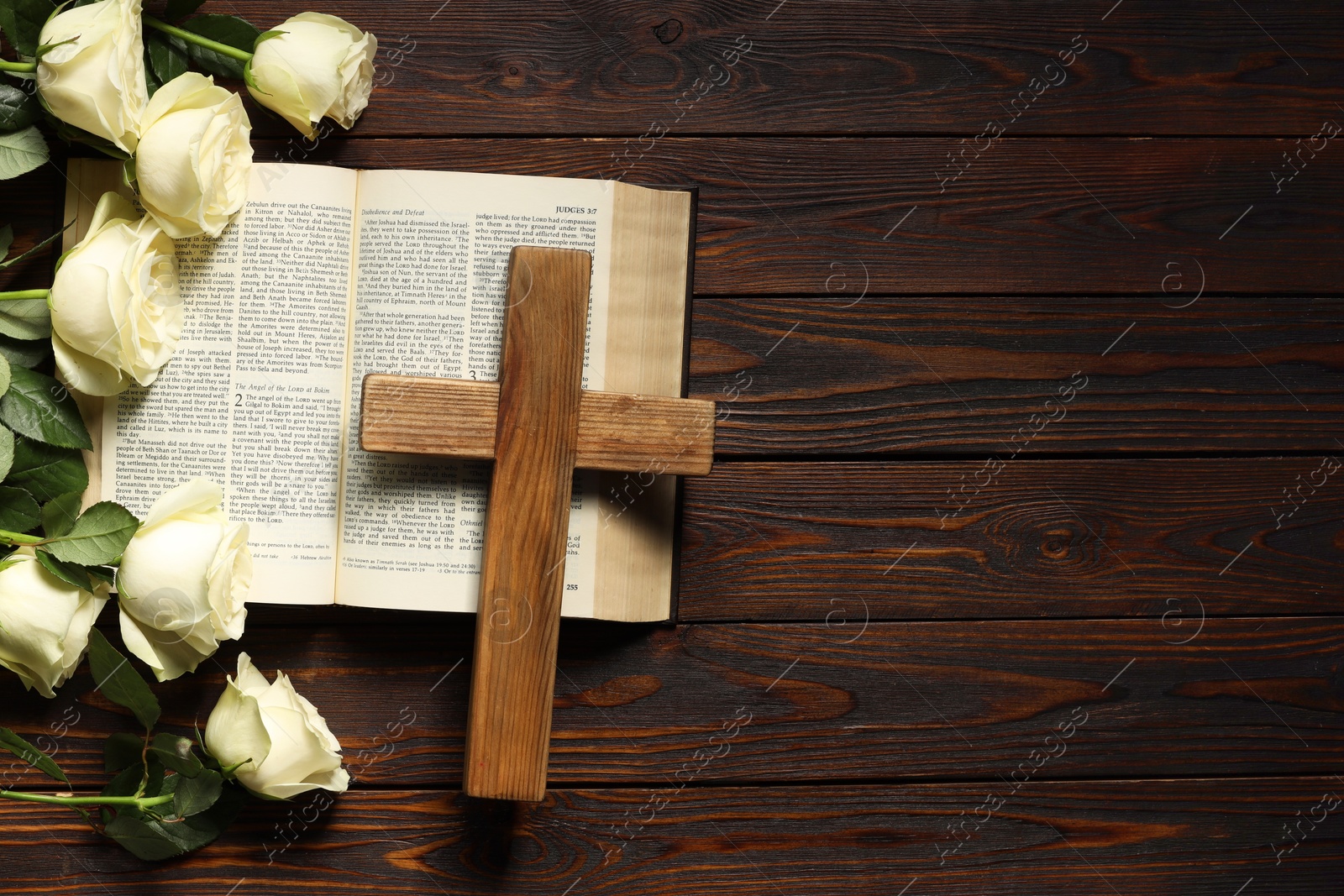 Photo of Bible, cross and roses on wooden table, top view with space for text. Religion of Christianity