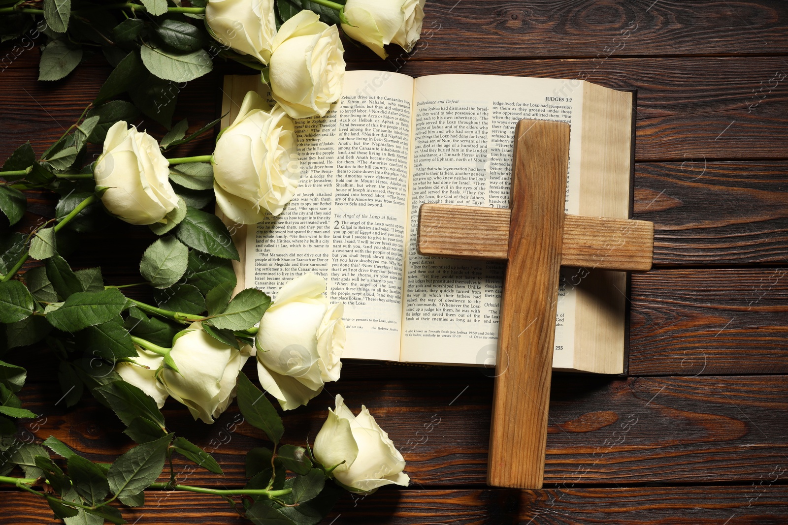 Photo of Bible, cross and roses on wooden table, top view. Religion of Christianity