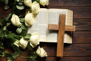 Bible, cross and roses on wooden table, top view. Religion of Christianity