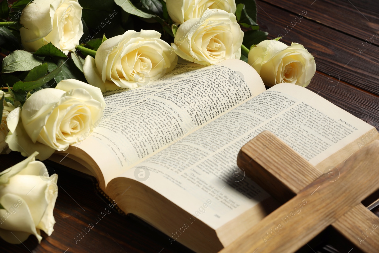 Photo of Bible, cross and roses on wooden table, closeup. Religion of Christianity