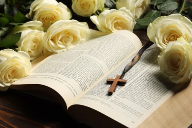 Photo of Bible, cross and roses on table, closeup. Religion of Christianity