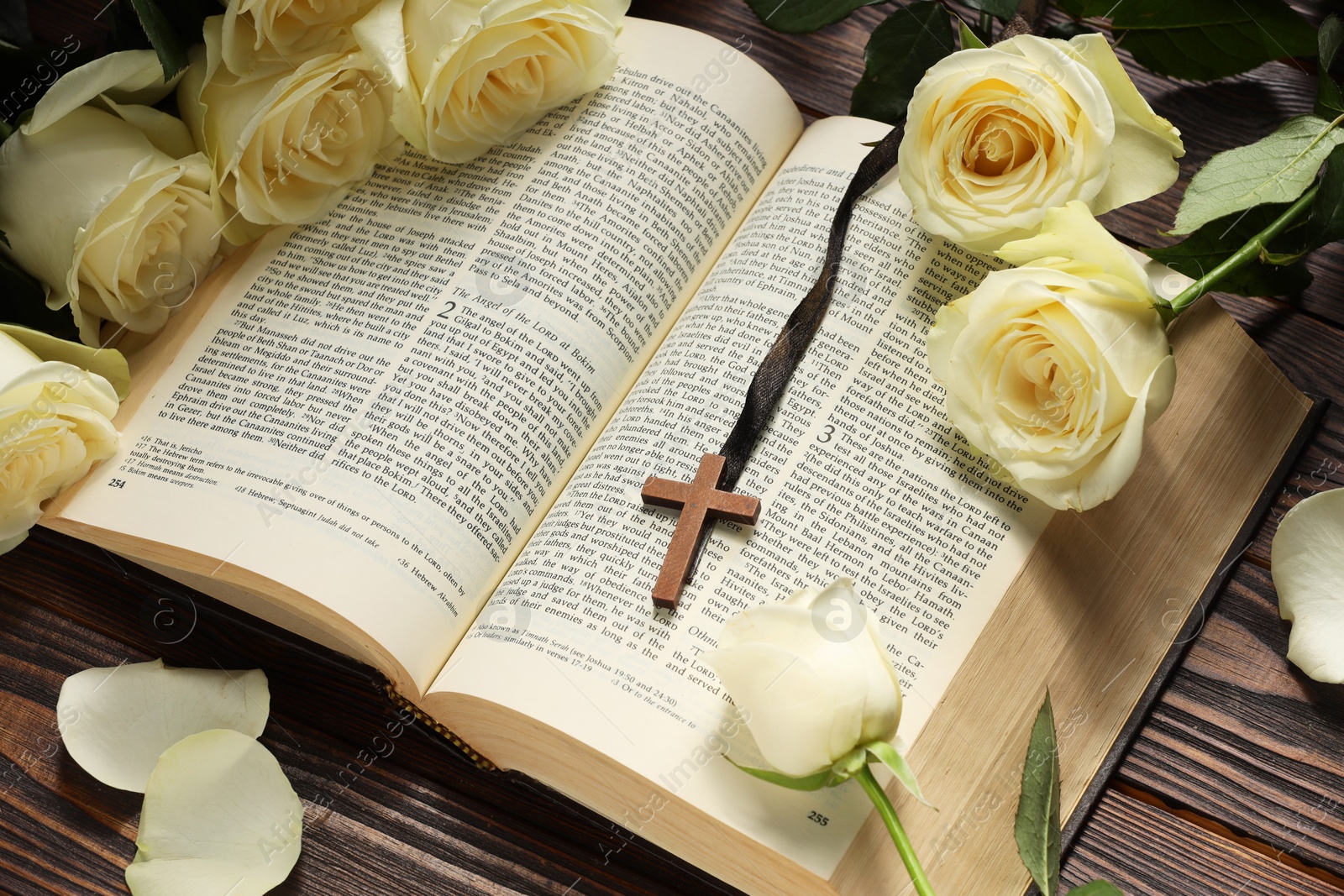 Photo of Bible, cross and roses on wooden table, closeup. Religion of Christianity