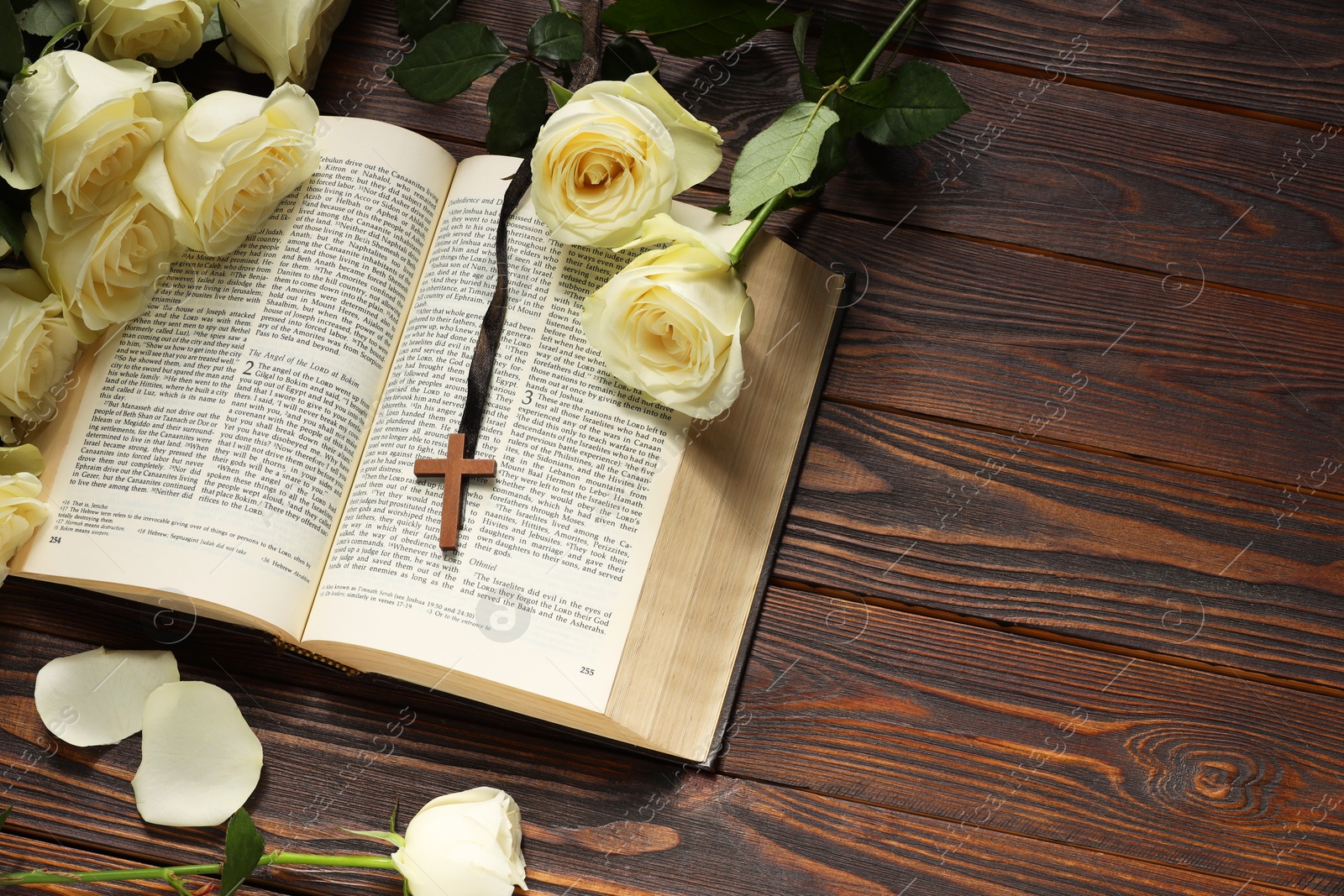 Photo of Bible, cross and roses on wooden table, above view with space for text. Religion of Christianity