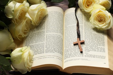 Photo of Bible, cross and roses on table, closeup. Religion of Christianity