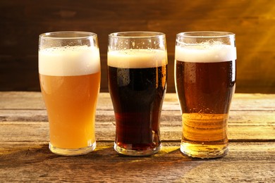 Glasses with different types of beer on wooden table