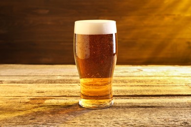 Glass of beer with froth on wooden table