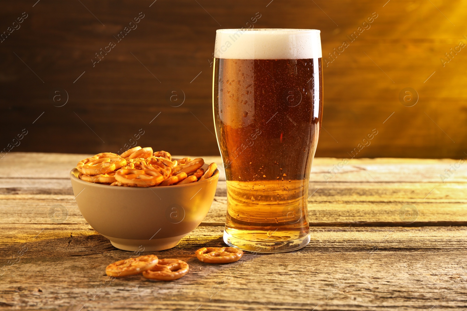 Photo of Glass of beer and pretzel crackers on wooden table