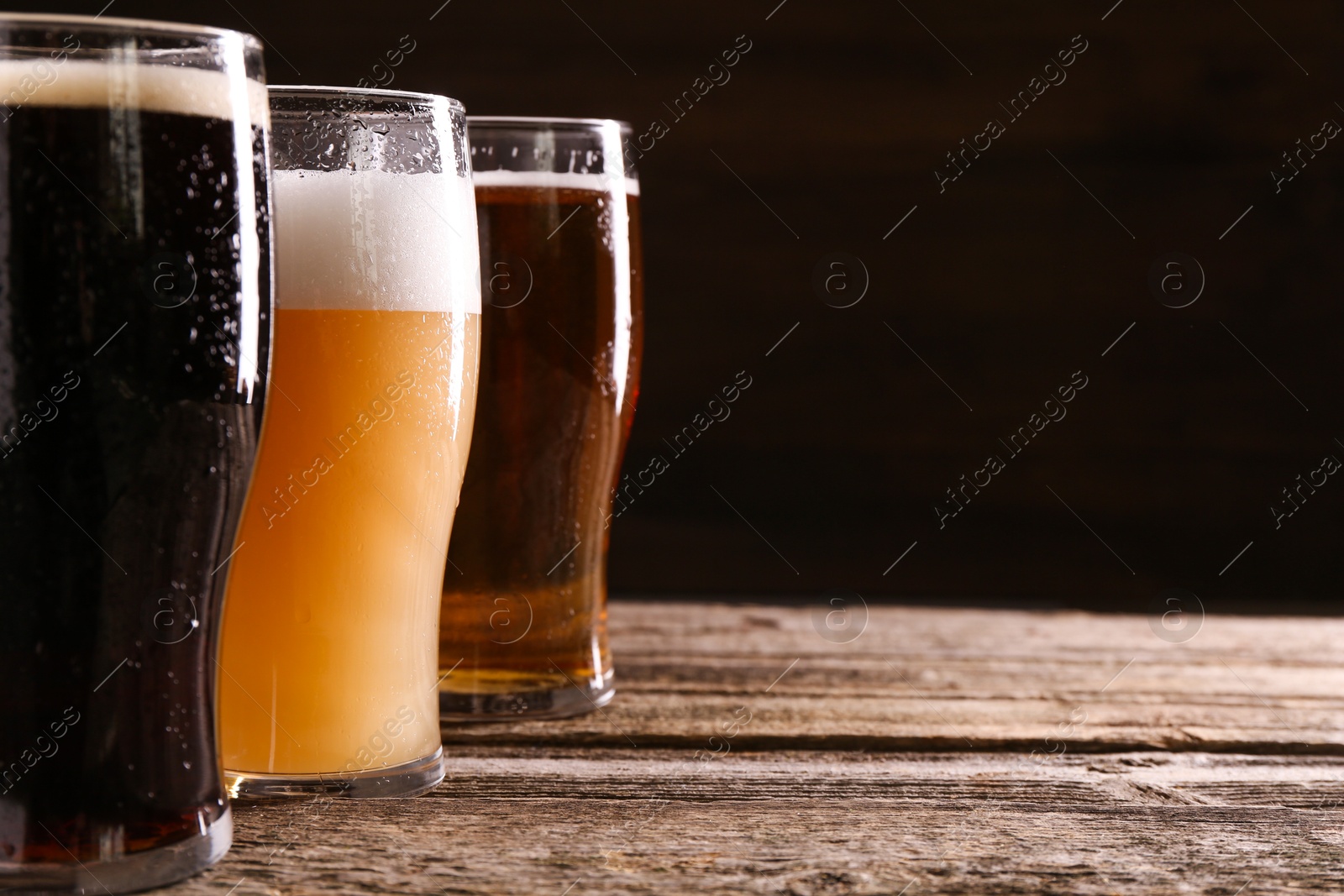 Photo of Glasses with different types of beer on wooden table, closeup. Space for text