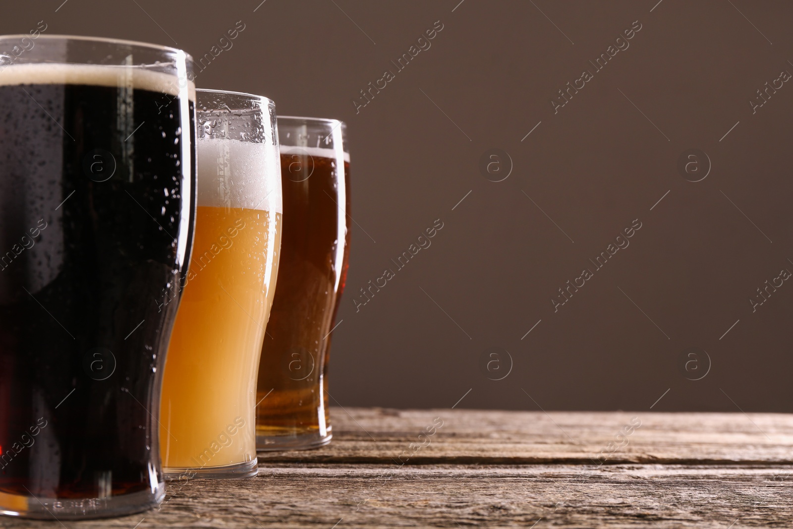 Photo of Glasses with different types of beer on wooden table, closeup. Space for text