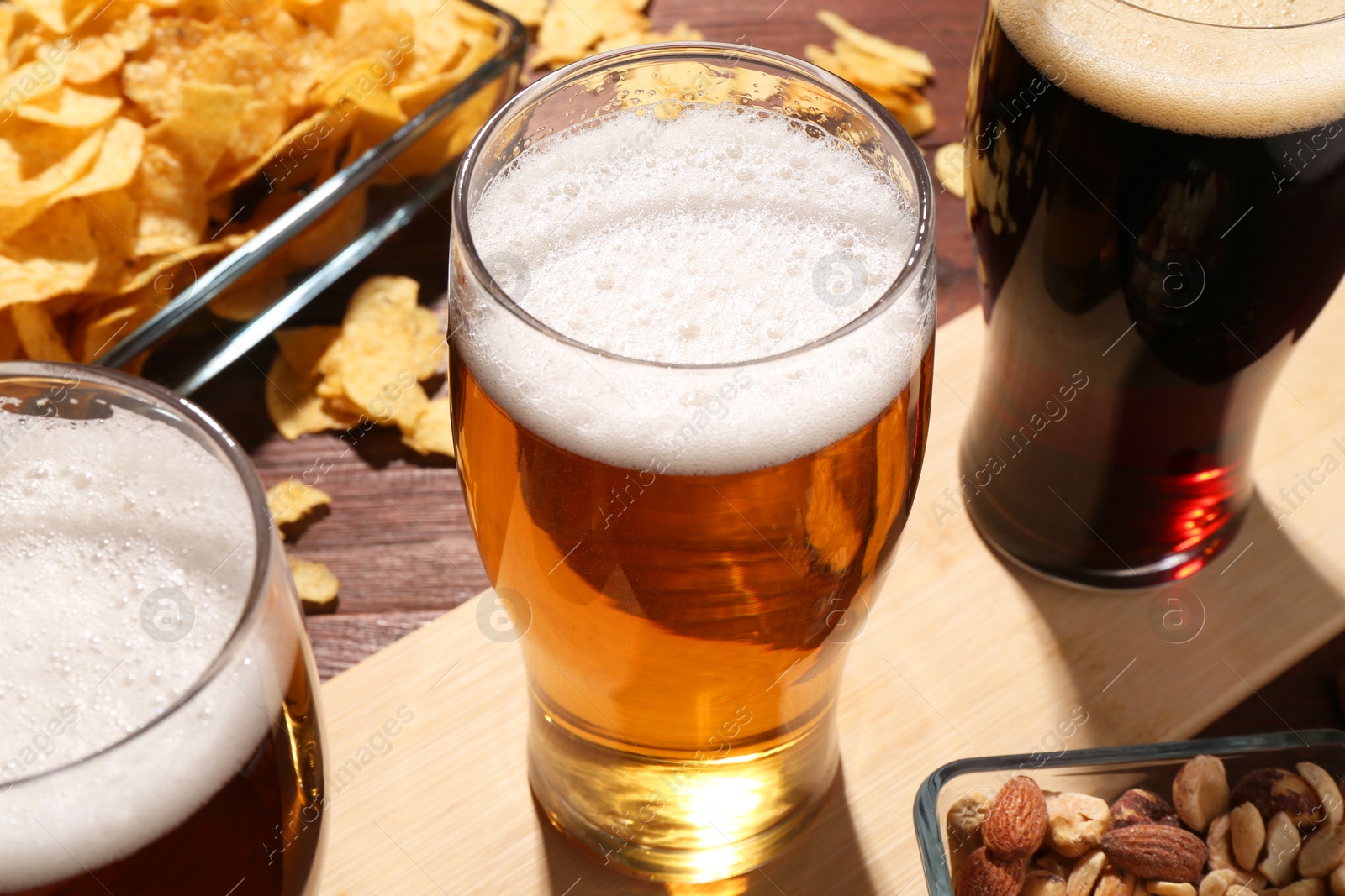 Photo of Glasses of beer and snacks on wooden table, closeup