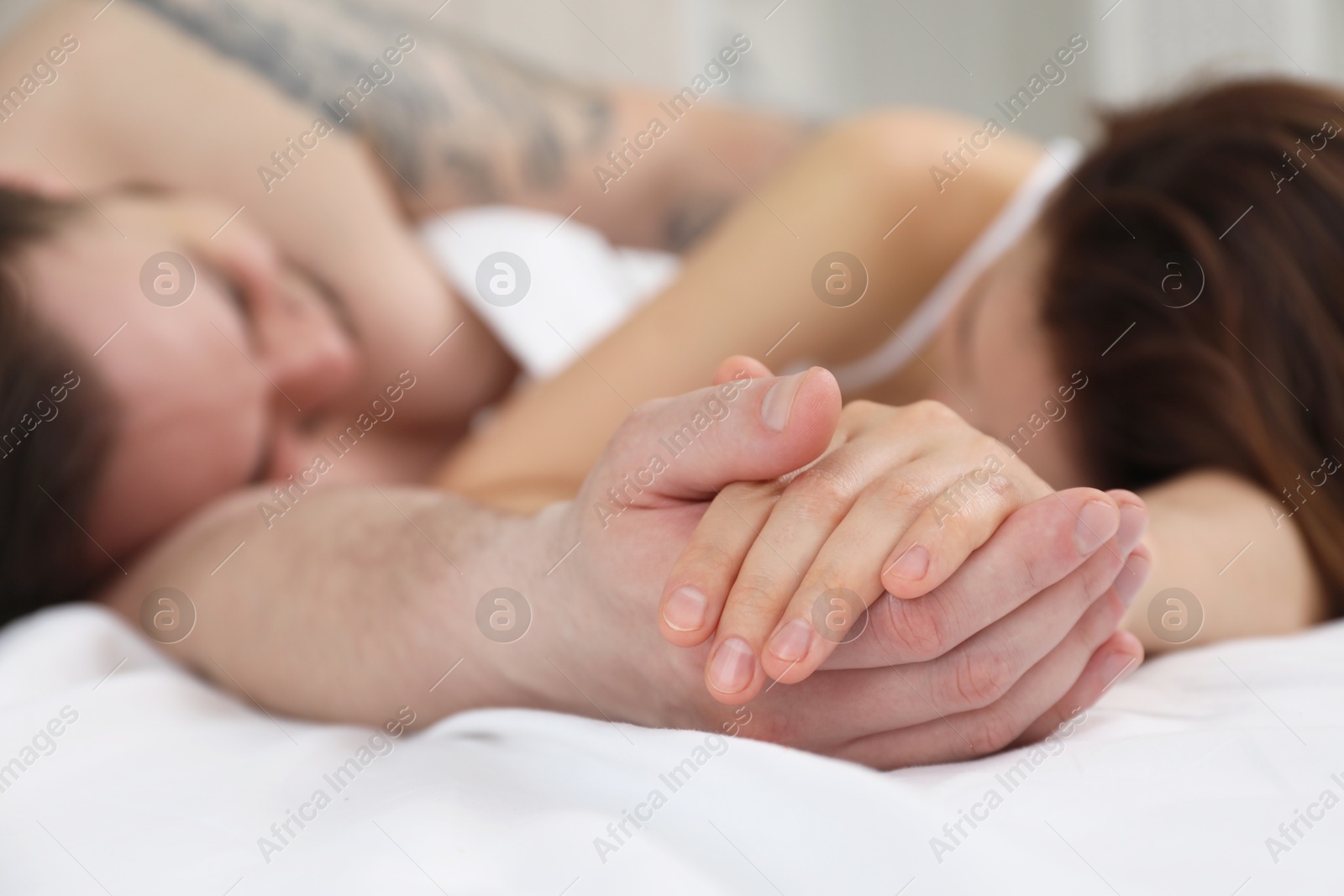 Photo of Lovely couple holding hands in bed, closeup