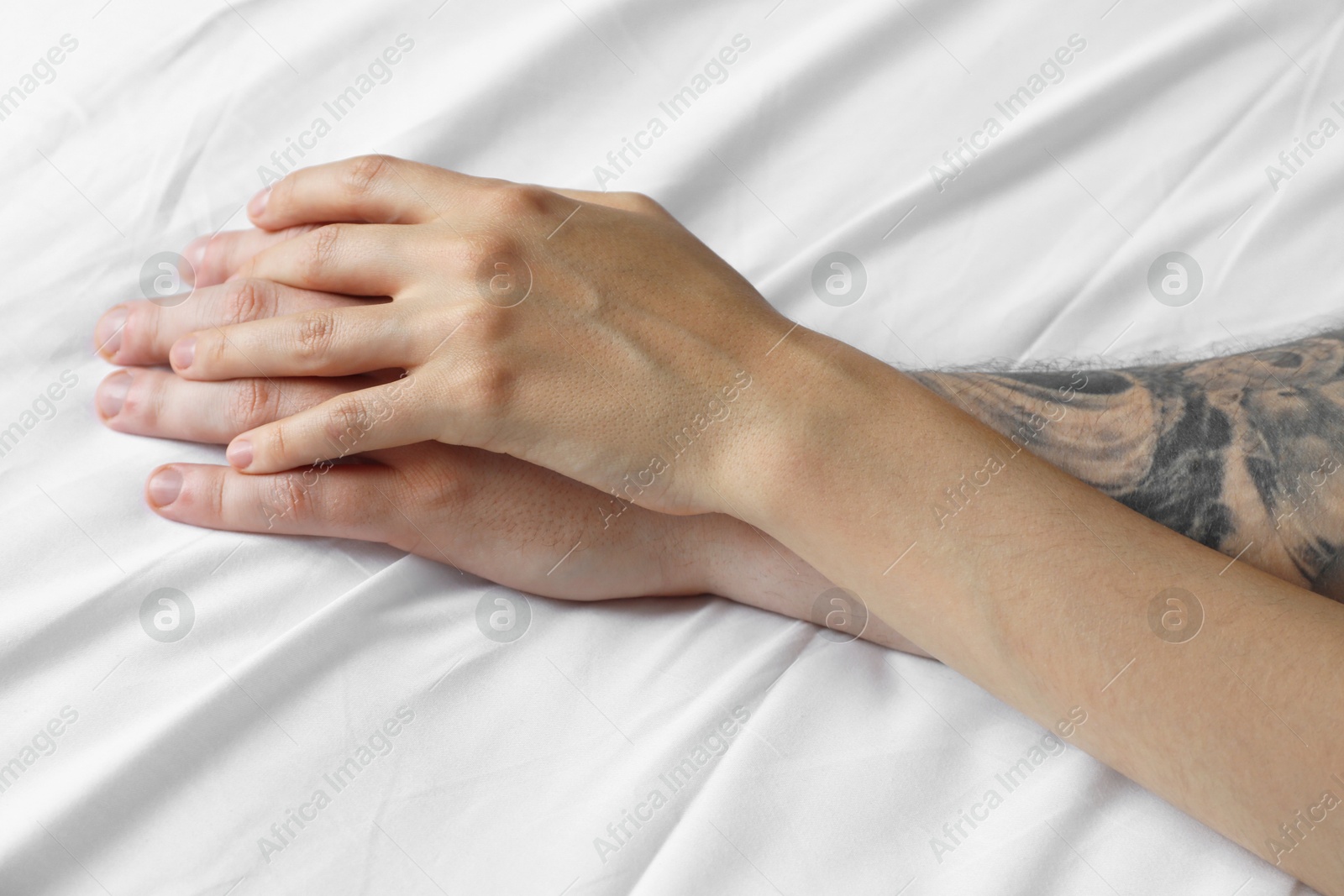 Photo of Lovely couple holding hands in bed, closeup