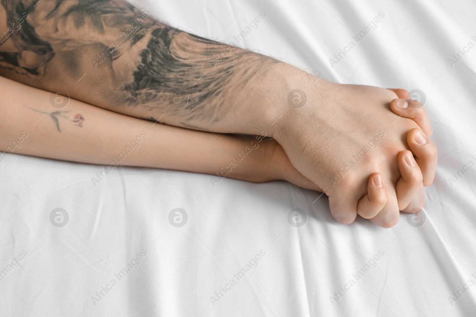 Photo of Lovely couple holding hands in bed, closeup