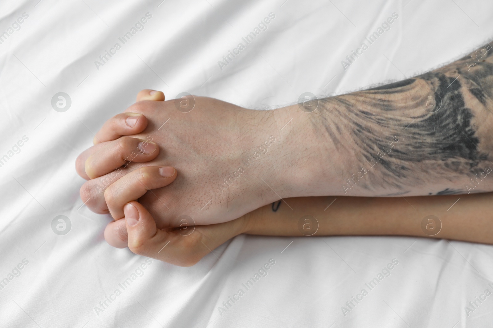 Photo of Lovely couple holding hands in bed, closeup