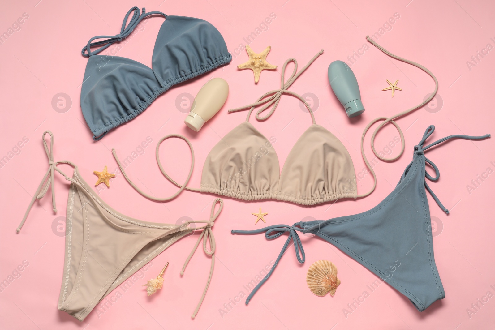 Photo of Beautiful swimsuits, seashells and sunscreens on pink background, flat lay