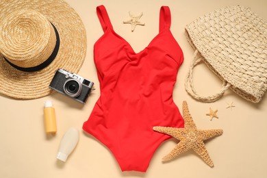 Photo of Flat lay composition with red swimsuit, hat and bag on beige background