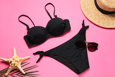 Black swimsuit, sunglasses, starfish and hat on pink background, flat lay