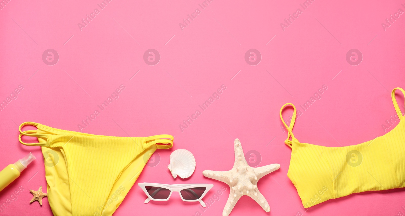 Photo of Flat lay composition with yellow swimsuit and sunglasses on pink background. Space for text