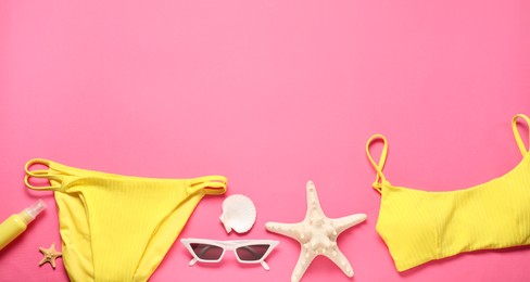 Flat lay composition with yellow swimsuit and sunglasses on pink background. Space for text