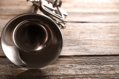 Photo of One trumpet on wooden table, closeup. Space for text