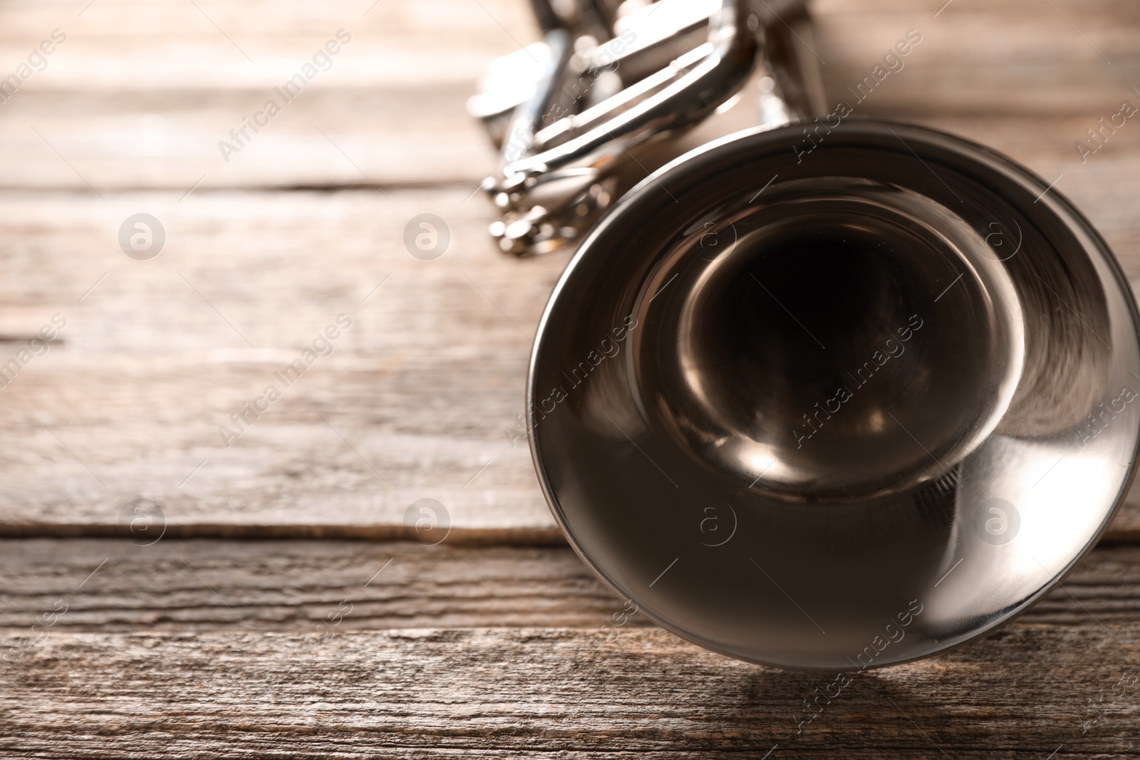 Photo of One trumpet on wooden table, closeup. Space for text