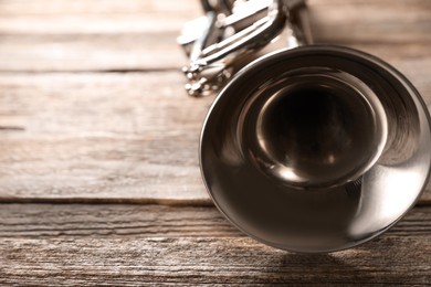 Photo of One trumpet on wooden table, closeup. Space for text