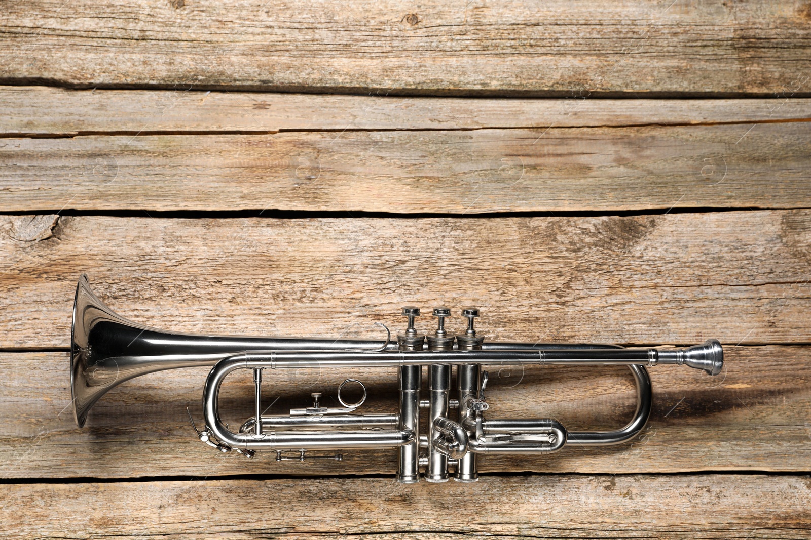 Photo of One trumpet on wooden table, top view. Space for text