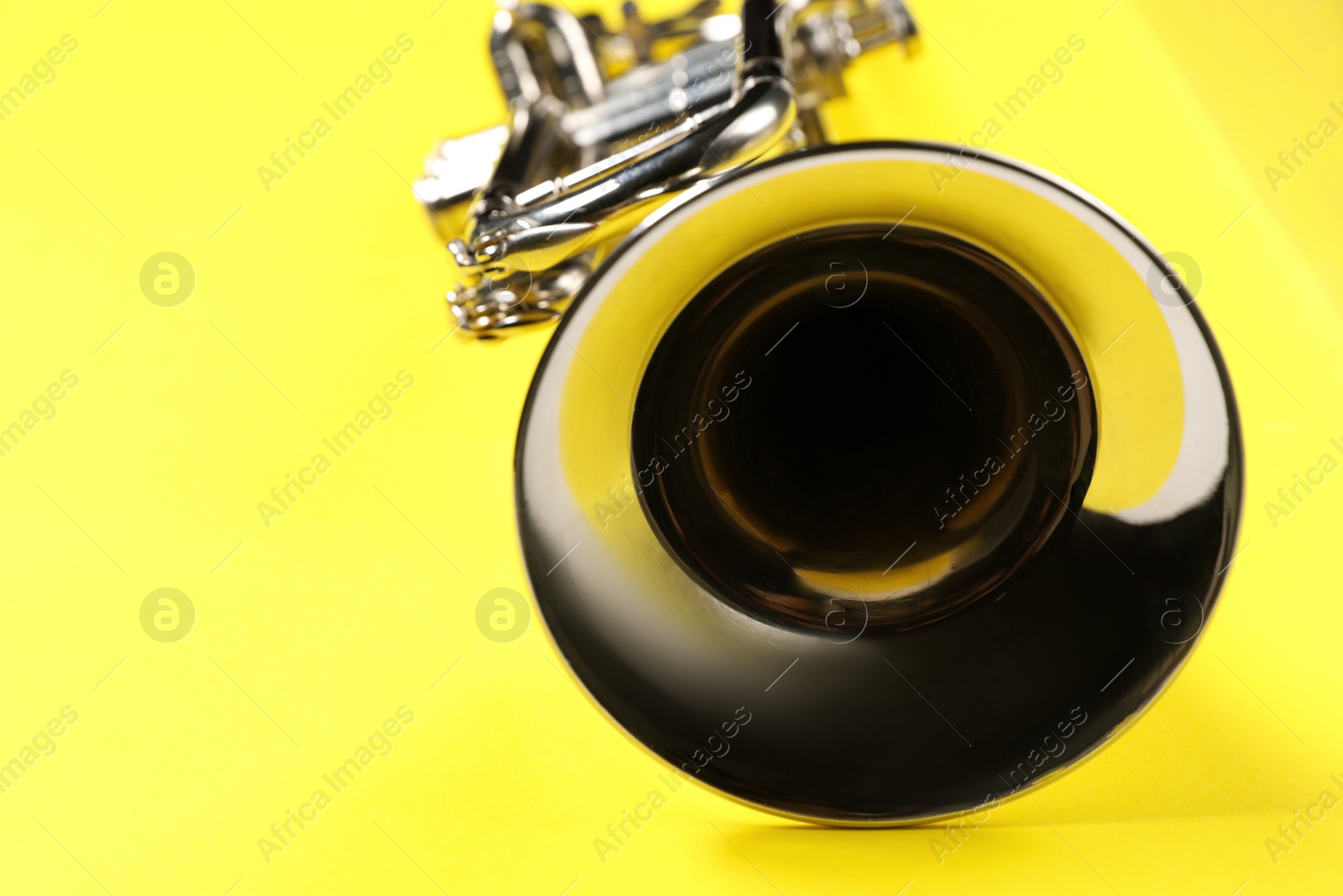 Photo of One trumpet on yellow background, closeup. Space for text