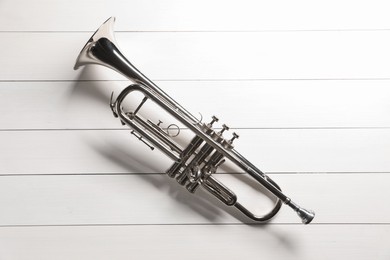 One trumpet on white wooden table, top view