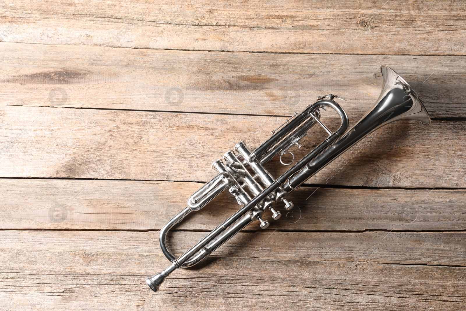 Photo of One trumpet on wooden table, top view. Space for text