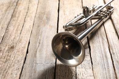 One trumpet on wooden table, closeup. Space for text