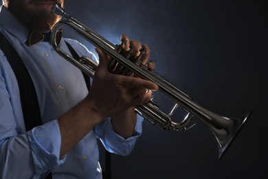 Photo of Professional musician holding trumpet on dark background, closeup