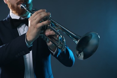 Photo of Professional musician playing trumpet on dark background, closeup
