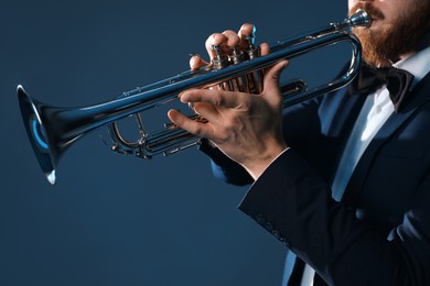Photo of Professional musician playing trumpet on dark background, closeup