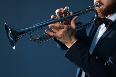 Professional musician playing trumpet on dark background, closeup