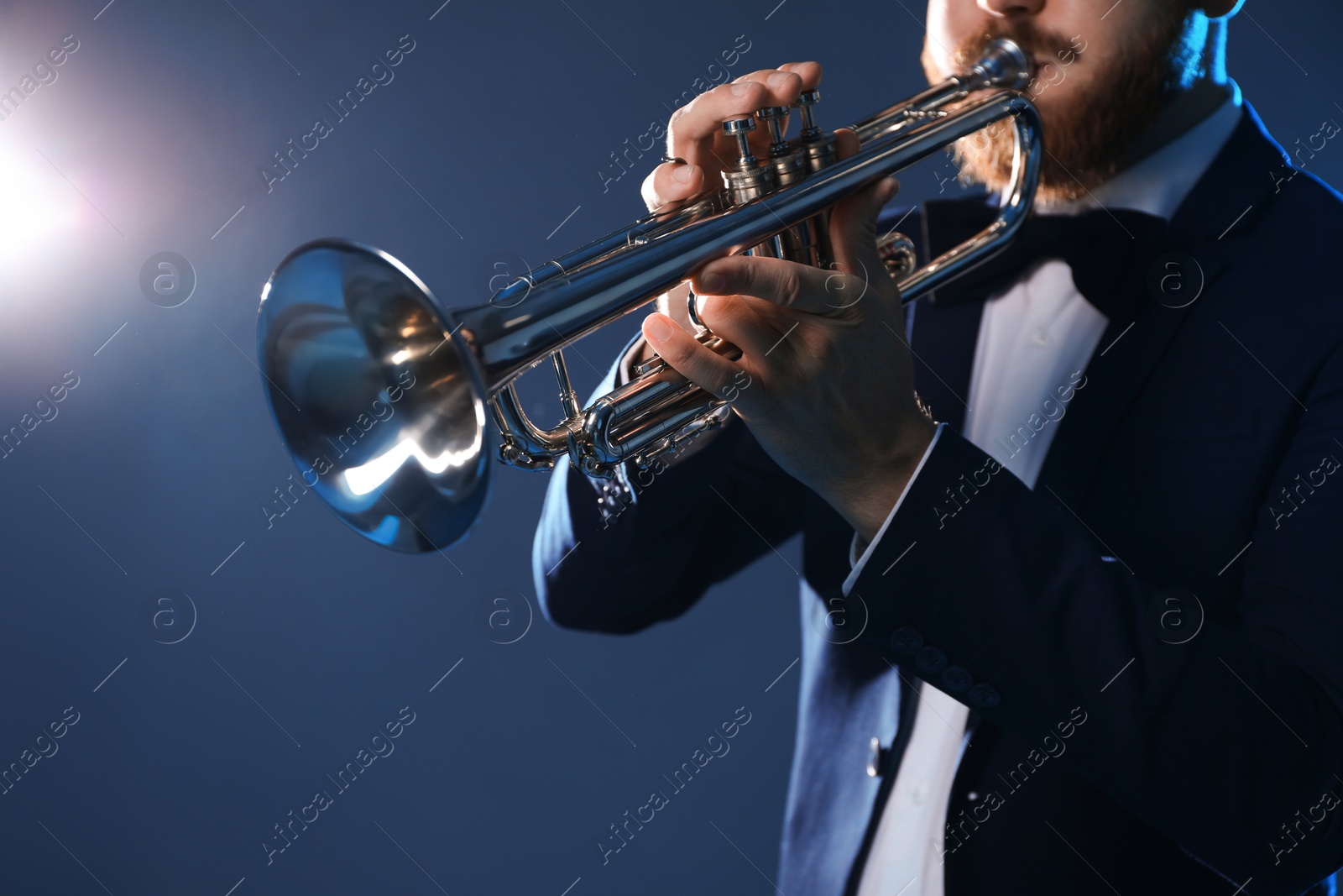 Photo of Professional musician playing trumpet on dark background, closeup