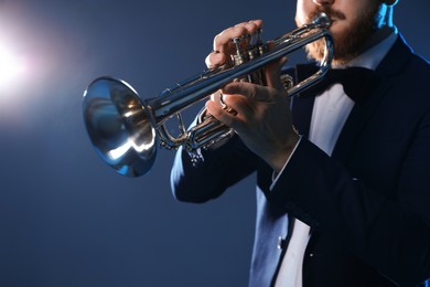 Professional musician playing trumpet on dark background, closeup