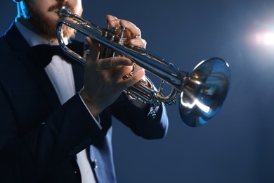 Photo of Professional musician playing trumpet on dark background, closeup