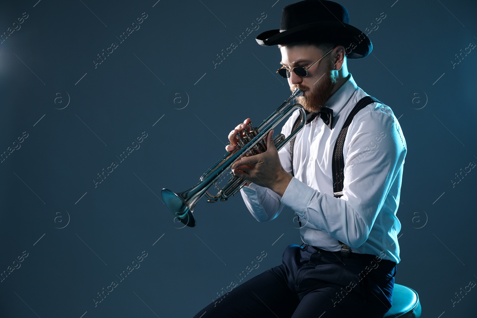 Photo of Professional musician playing trumpet on dark background. Space for text