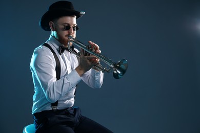 Photo of Professional musician playing trumpet on dark background. Space for text