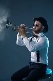 Professional musician playing trumpet on dark background