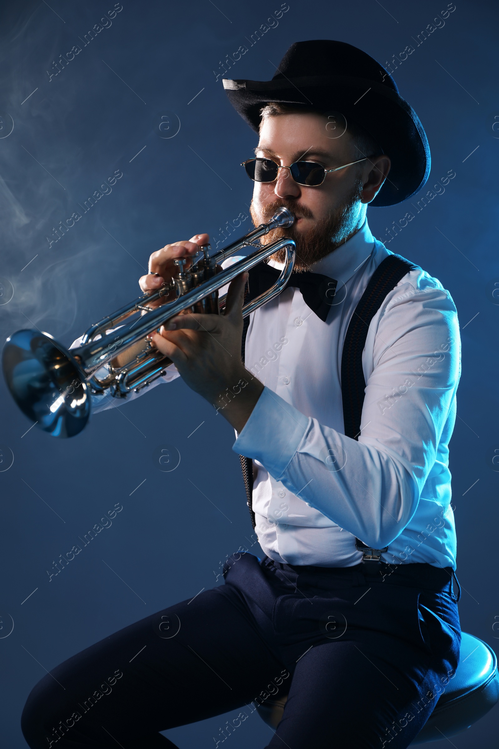 Photo of Professional musician playing trumpet on dark background with smoke