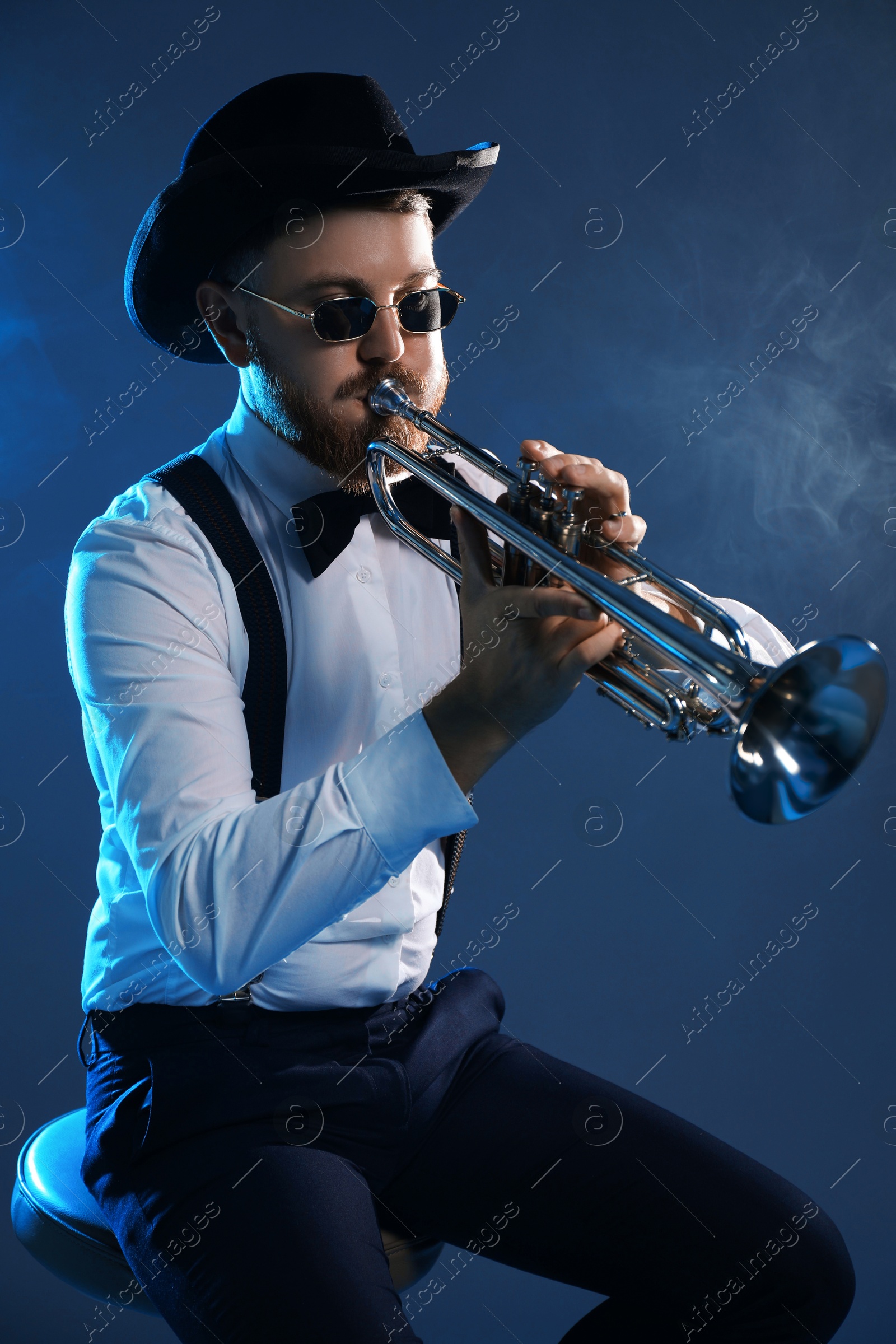 Photo of Professional musician playing trumpet on dark background with smoke