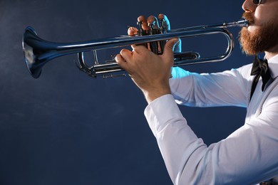 Photo of Professional musician playing trumpet on dark background with smoke, closeup