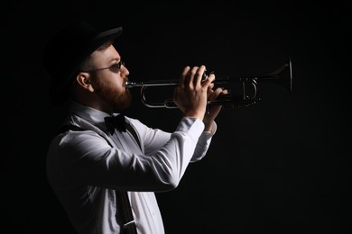 Professional musician playing trumpet on black background