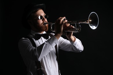 Professional musician playing trumpet on black background