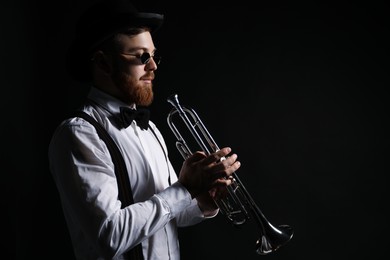 Professional musician with trumpet on black background