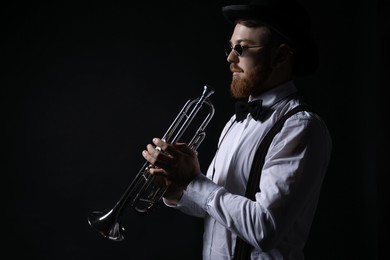 Photo of Professional musician with trumpet on black background